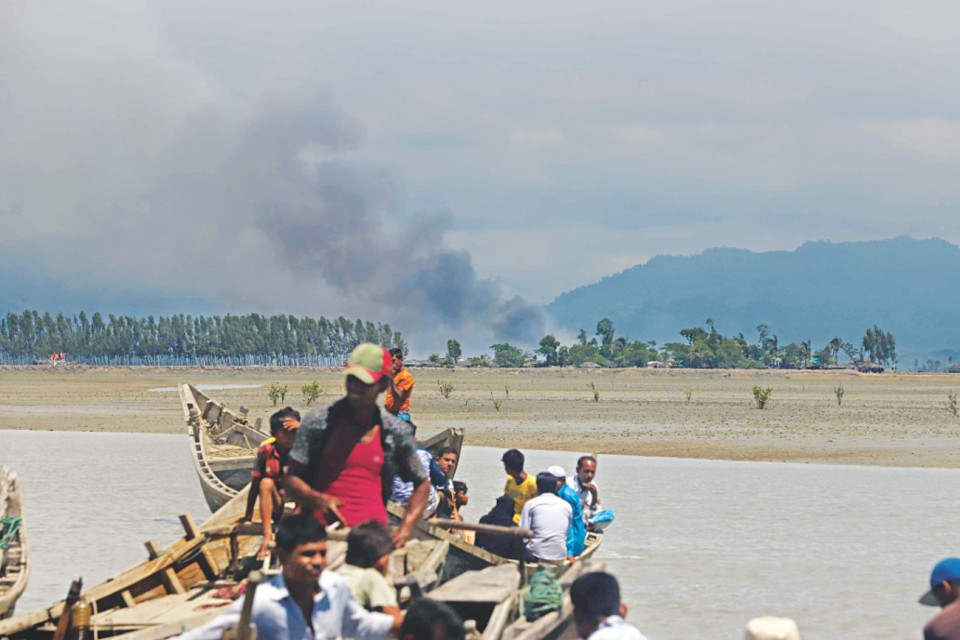 Boats with more refugees arrive as smoke billows from a village on the Myanmar side of the border