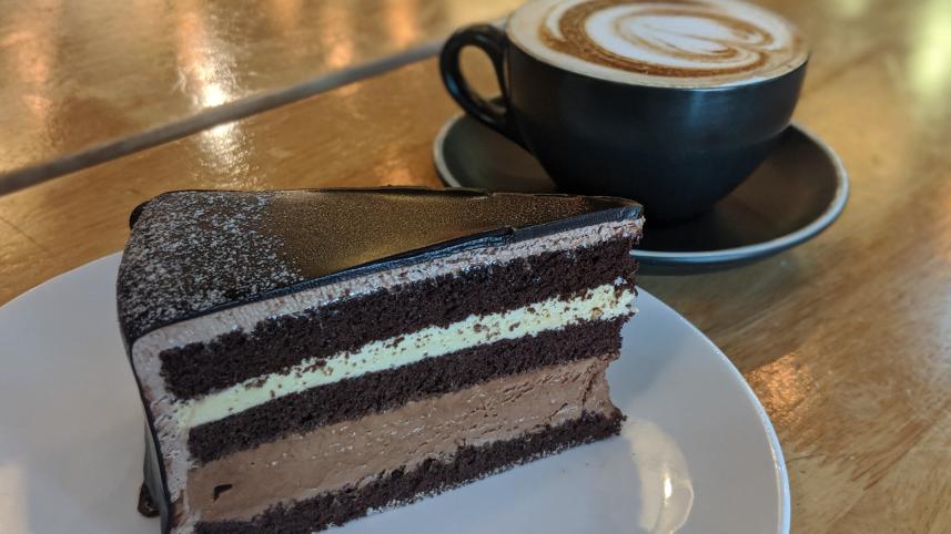 A slice of cake with a warm cup of coffee.