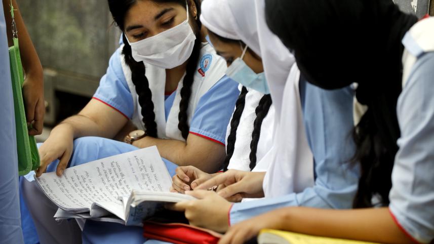 A photo of girls sitting together and reading a textbook