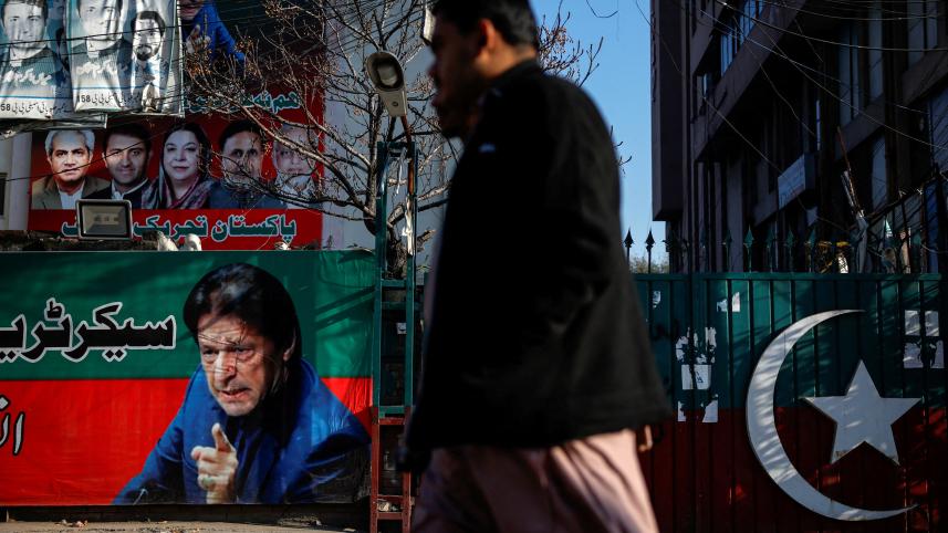 People walk past a banner with a picture of the former Prime Minister Imran Khan outside the party office of Pakistan Tehreek-e-Insaf (PTI), a day after the general election, in Lahore, Pakistan, February 9, 2024. PHOTO: REUTERS