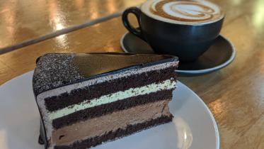 A slice of cake with a warm cup of coffee.