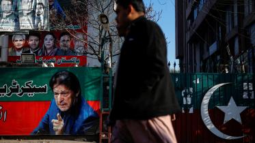 People walk past a banner with a picture of the former Prime Minister Imran Khan outside the party office of Pakistan Tehreek-e-Insaf (PTI), a day after the general election, in Lahore, Pakistan, February 9, 2024. PHOTO: REUTERS