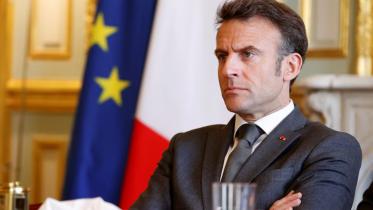 Macron sitting near French flag